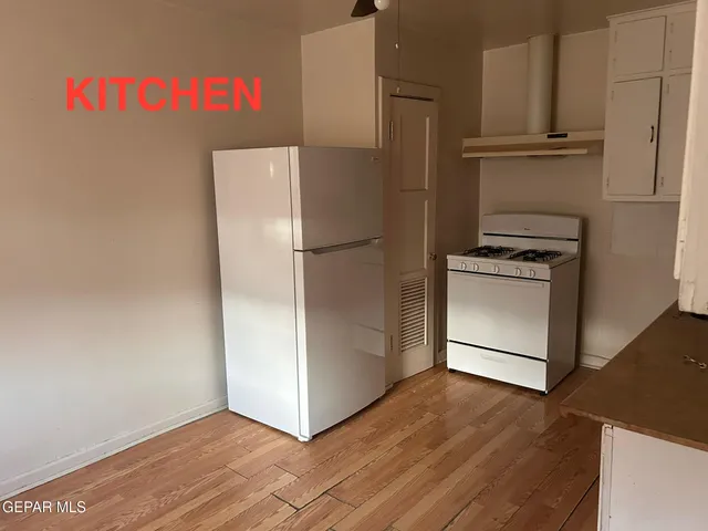 a white refrigerator freezer and a wooden floor