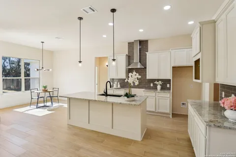 a kitchen with stainless steel appliances kitchen island granite countertop a sink a stove a refrigerator and white cabinets