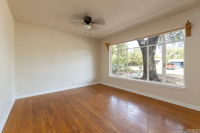 a view of an empty room with wooden floor and a window