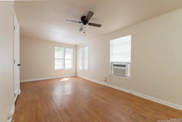 a view of an empty room with a window and wooden floor