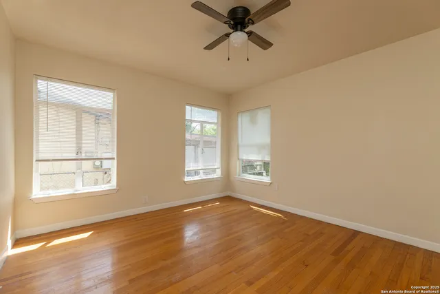a view of empty room with wooden floor and fan