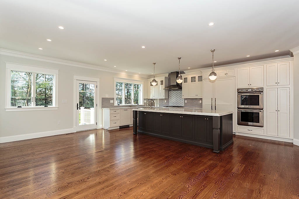 180 Ridge Street Winchester, MA 01890 - Photo 12 of 30 a large white kitchen with wooden floors and stainless steel appliances