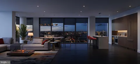 a living room with couches and kitchen view with wooden floor