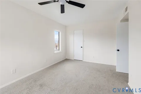 an empty room with a ceiling fan and window