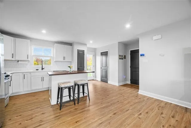 a open kitchen with white cabinets wooden floor and stainless steel appliances