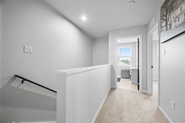 a view of a hallway with white walls and stairs
