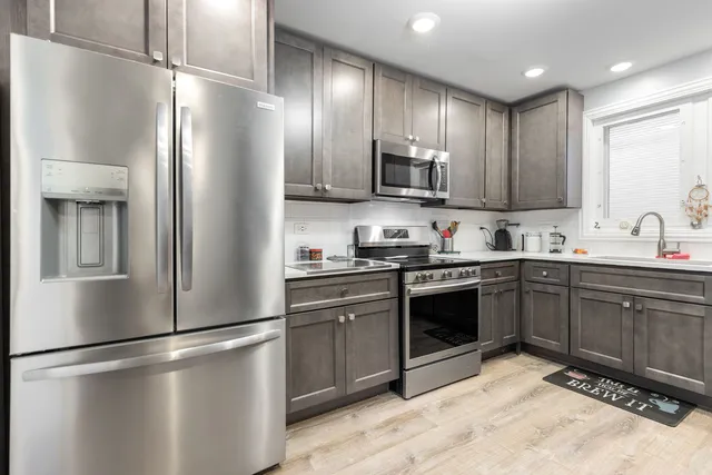 a kitchen with stainless steel appliances granite countertop a refrigerator a sink and a stove