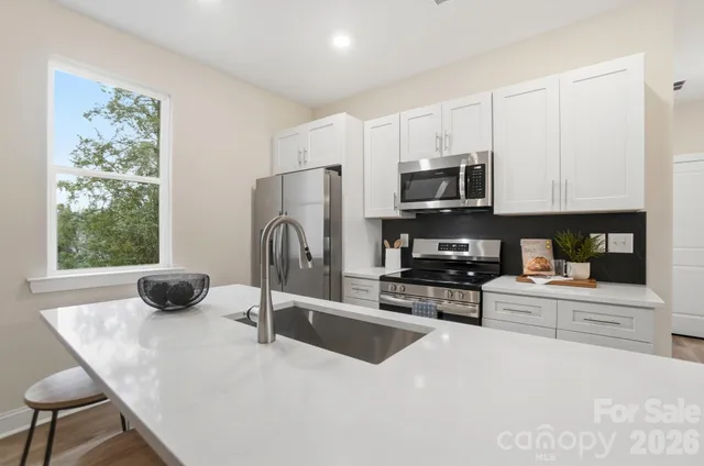 a kitchen with stainless steel appliances a stove a sink a microwave a refrigerator a counter space and cabinets