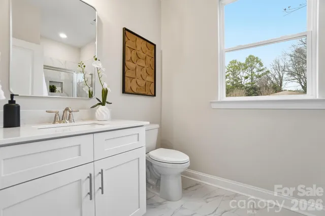 a bathroom with a granite countertop sink mirror vanity and toilet