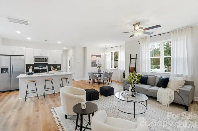 a living room with furniture kitchen view and a large window