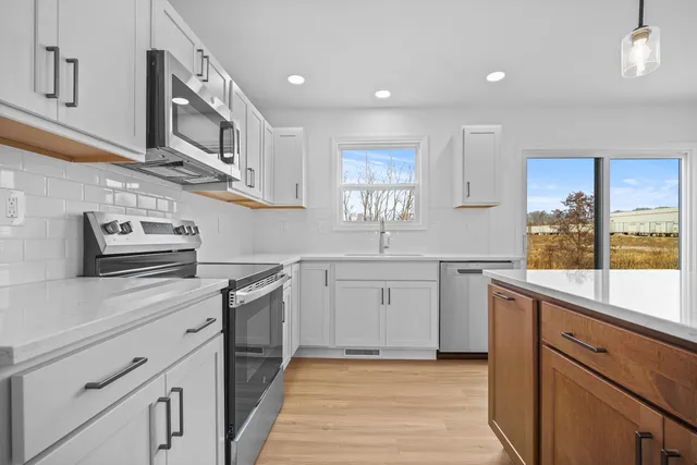 a kitchen with cabinets stainless steel appliances a sink and a window