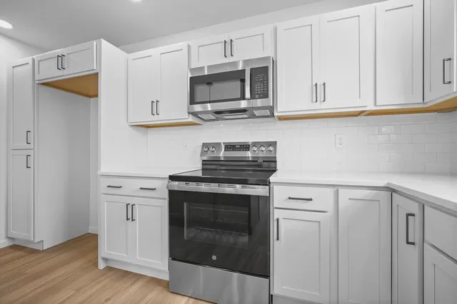 a kitchen with white cabinets and stainless steel appliances