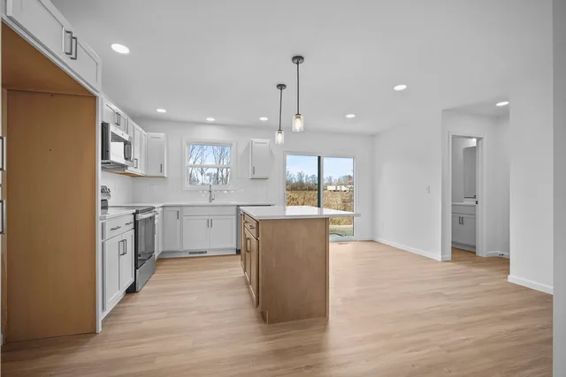 a large kitchen with a center island wooden floor stainless steel appliances and a window