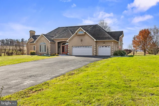 a front view of a house with a big yard and large trees