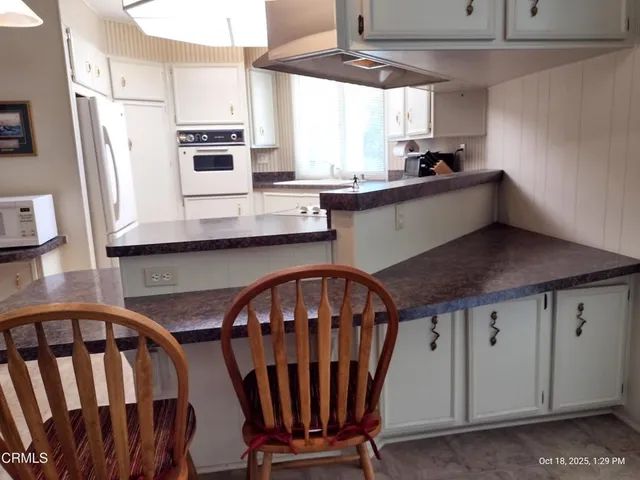 a kitchen with stainless steel appliances granite countertop a sink a stove a refrigerator a washer and dryer