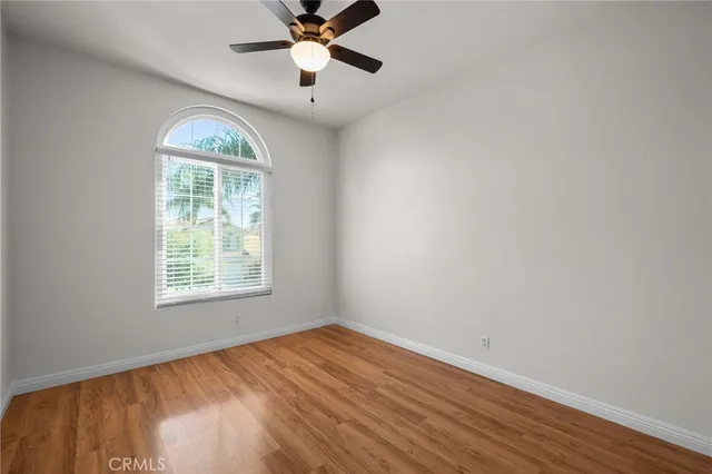 an empty room with wooden floor fan and windows