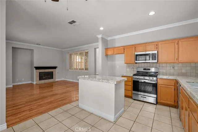 a kitchen with stainless steel appliances granite countertop a stove top oven a sink dishwasher and a refrigerator with wooden floor