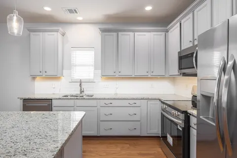a kitchen with stainless steel appliances granite countertop a sink stove and refrigerator