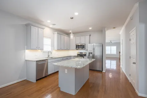 a large kitchen with stainless steel appliances granite countertop a lot of counter space and wooden floors