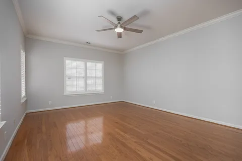an empty room with wooden floor and ceiling fan
