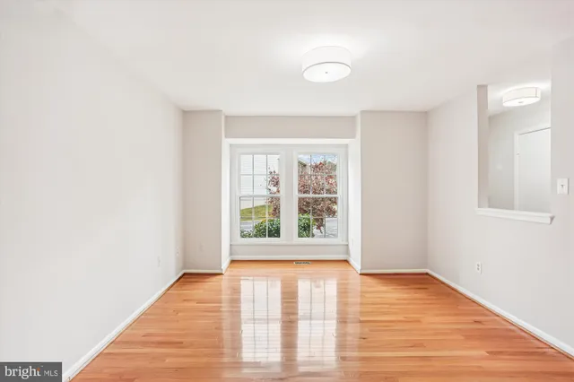 a view of an empty room with wooden floor and stairs