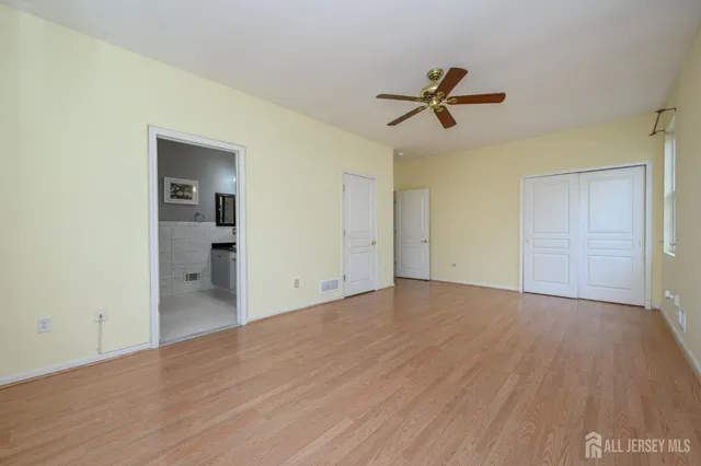 a view of empty room with wooden floor and ceiling fan