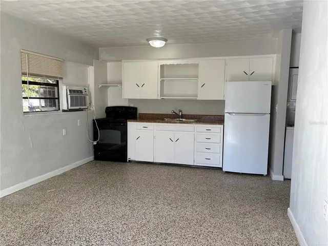 a kitchen with granite countertop a white refrigerator oven a sink with cabinets and wooden floor