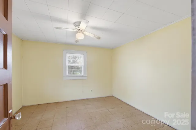 an empty room with a window and ceiling fan