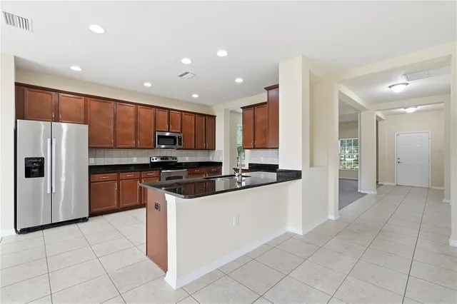 a kitchen with stainless steel appliances granite countertop a refrigerator and a stove top oven