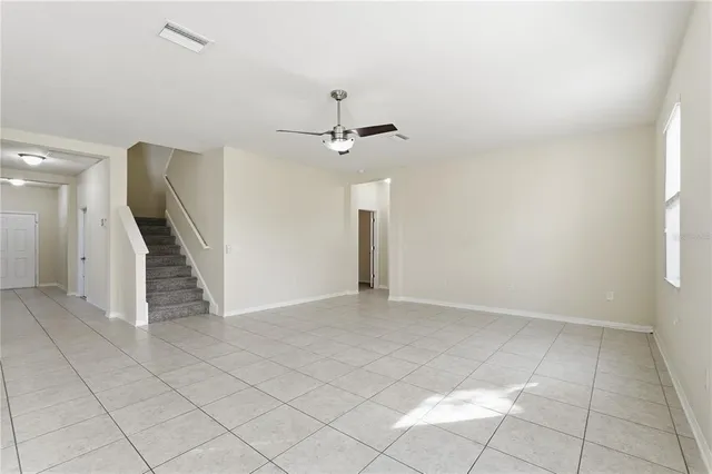 an empty room with a ceiling fan and carpet