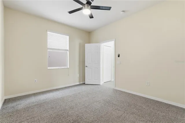 an empty room with a window and ceiling fan