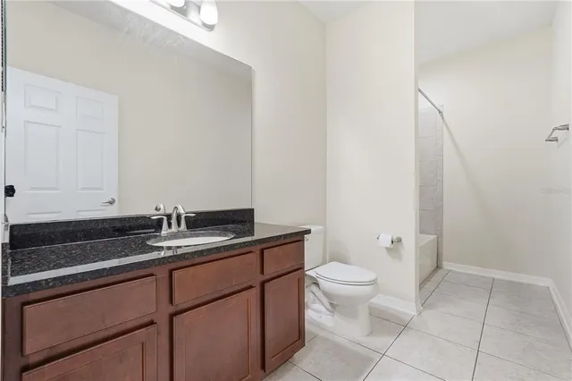 a bathroom with a granite countertop sink a toilet and a mirror