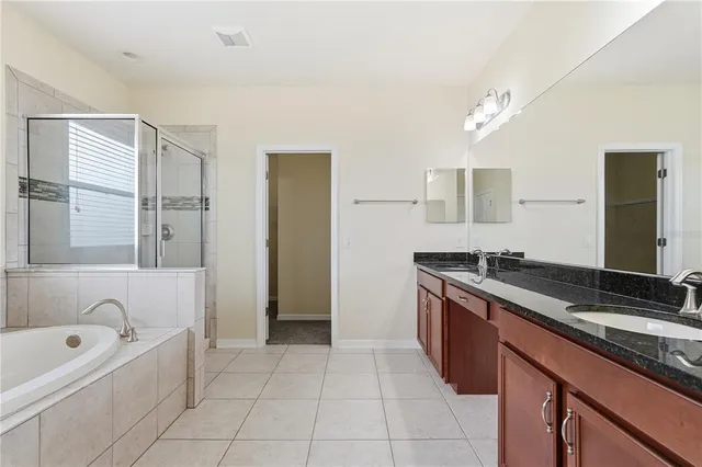 a spacious bathroom with a granite countertop sink a bathtub and mirror
