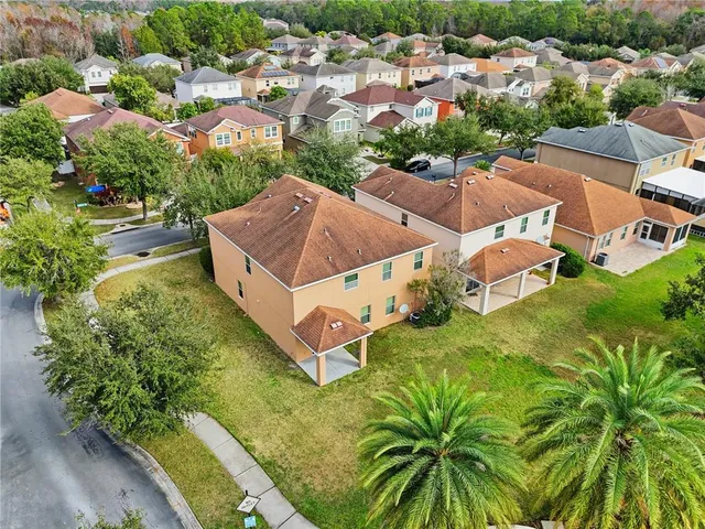 an aerial view of residential houses with outdoor space and trees