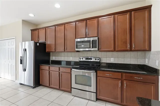 a kitchen with stainless steel appliances granite countertop a refrigerator stove top oven and sink