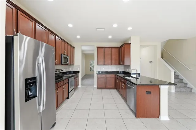 a large kitchen with stainless steel appliances kitchen island granite countertop a refrigerator and a stove top oven