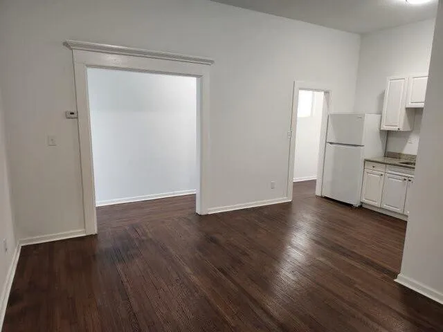 an empty room with wooden floor cabinet and windows