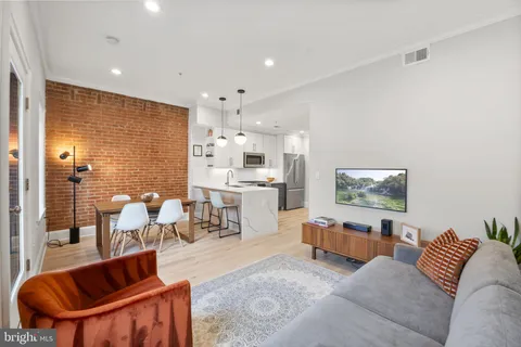 a living room with furniture potted plant and kitchen view