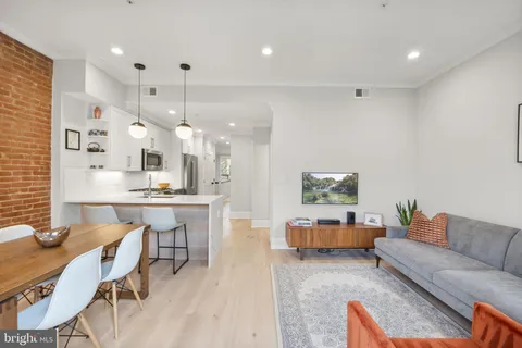 a living room with furniture kitchen view and a chandelier