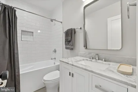 a bathroom with a granite countertop sink a toilet and a bathtub