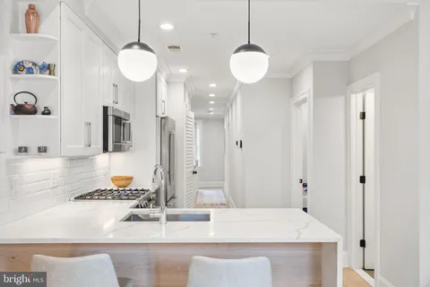 a kitchen with granite countertop a sink a stove and a refrigerator