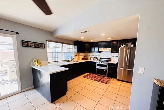 a living room with stainless steel appliances furniture a rug and a view of kitchen