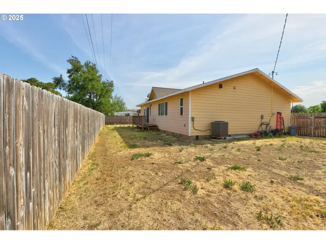 a view of a house with backyard and wooden fence