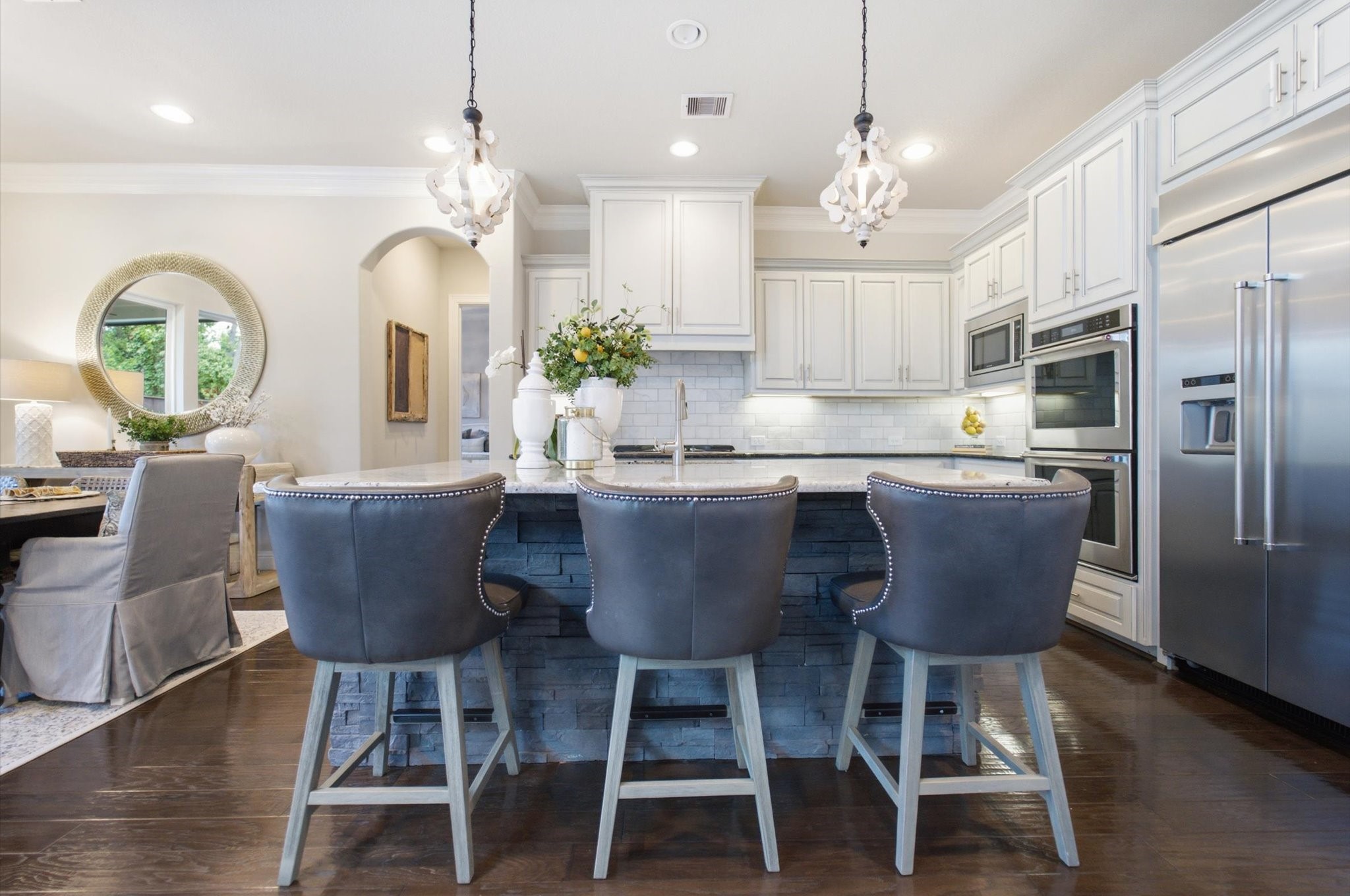 23722 Thortons Park Lane Spring, TX 77389 - Photo 22 of 48 This kitchen features a modern design with white cabinetry, stainless steel appliances, and a large island with stylish barstools. Pendant lighting adds elegance, while an open layout connects to a dining area with tasteful decor. Perfect for entertaining and family gatherings.