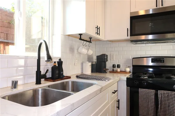 a kitchen with stainless steel appliances a sink a stove and a microwave