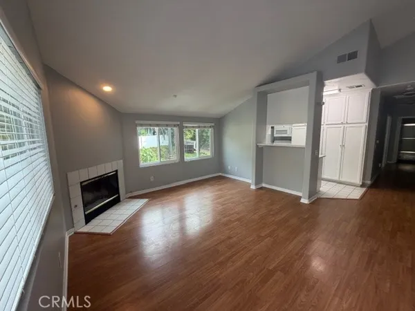an empty room with wooden floor fireplace and windows