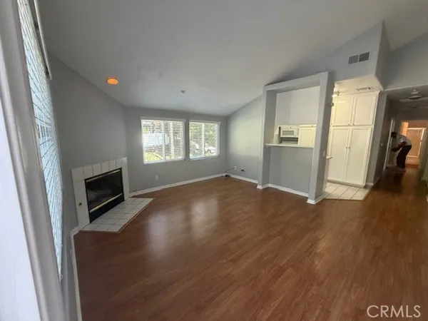 an empty room with windows fireplace and wooden floor