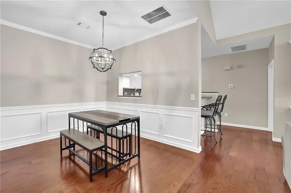 a dining room with wooden floor a chandelier a wooden table and chairs
