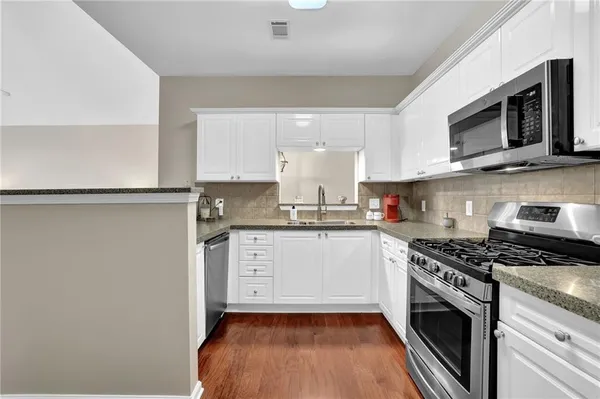 a kitchen with granite countertop white cabinets stainless steel appliances and sink