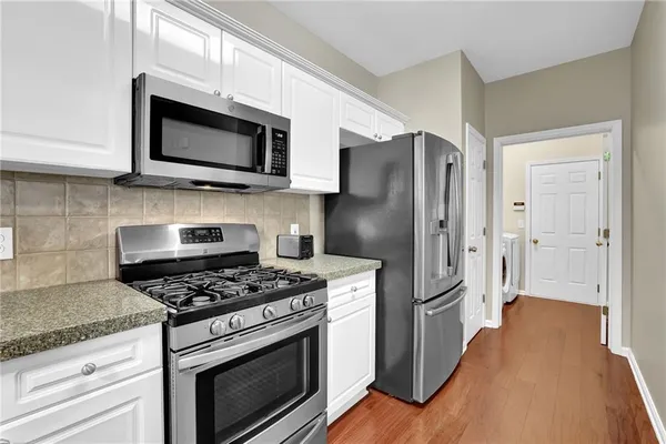 a kitchen with stainless steel appliances white cabinets a stove a microwave and a refrigerator